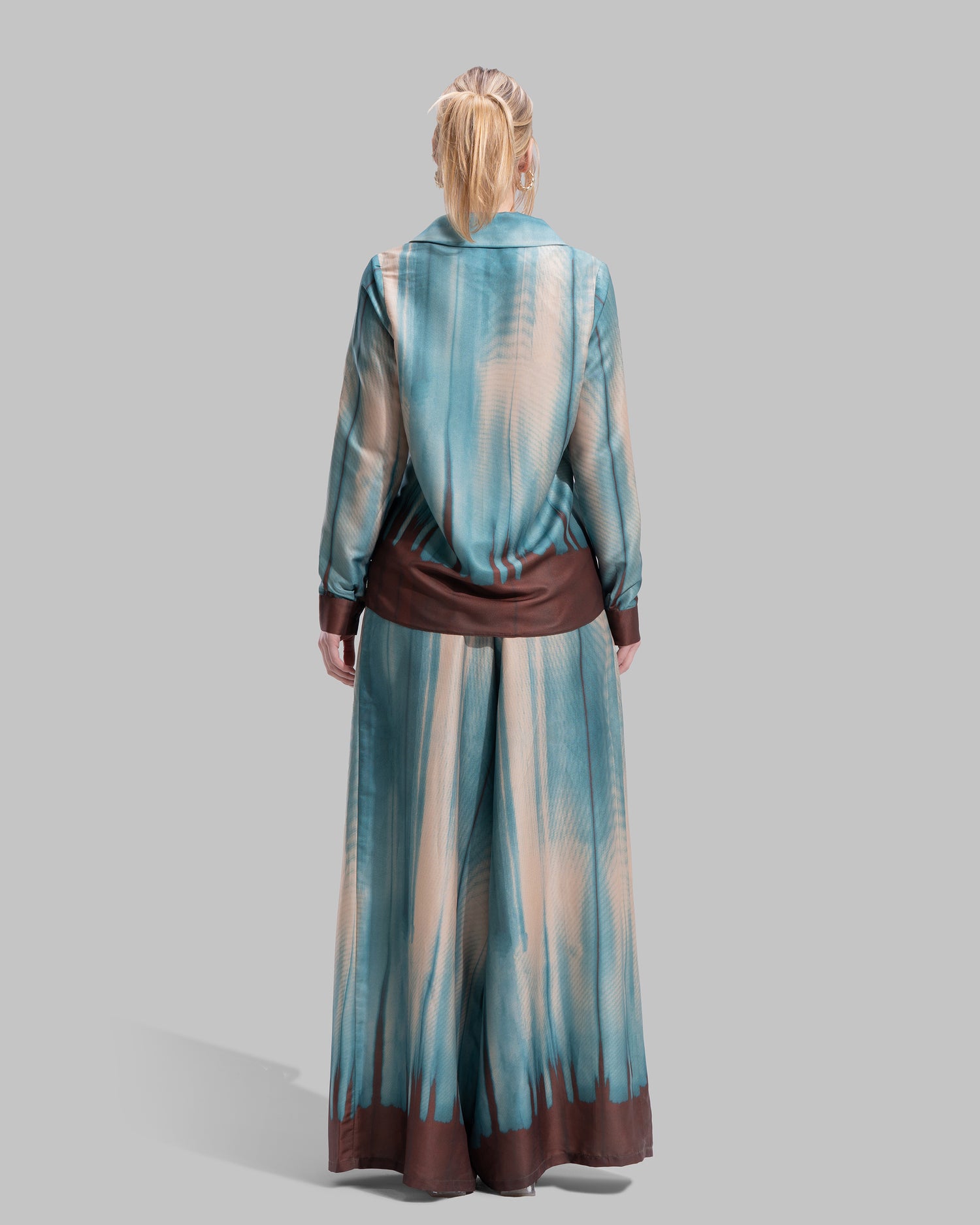 A long-sleeved button-down shirt featuring a teal and cream gradient print with a dark brown hem.