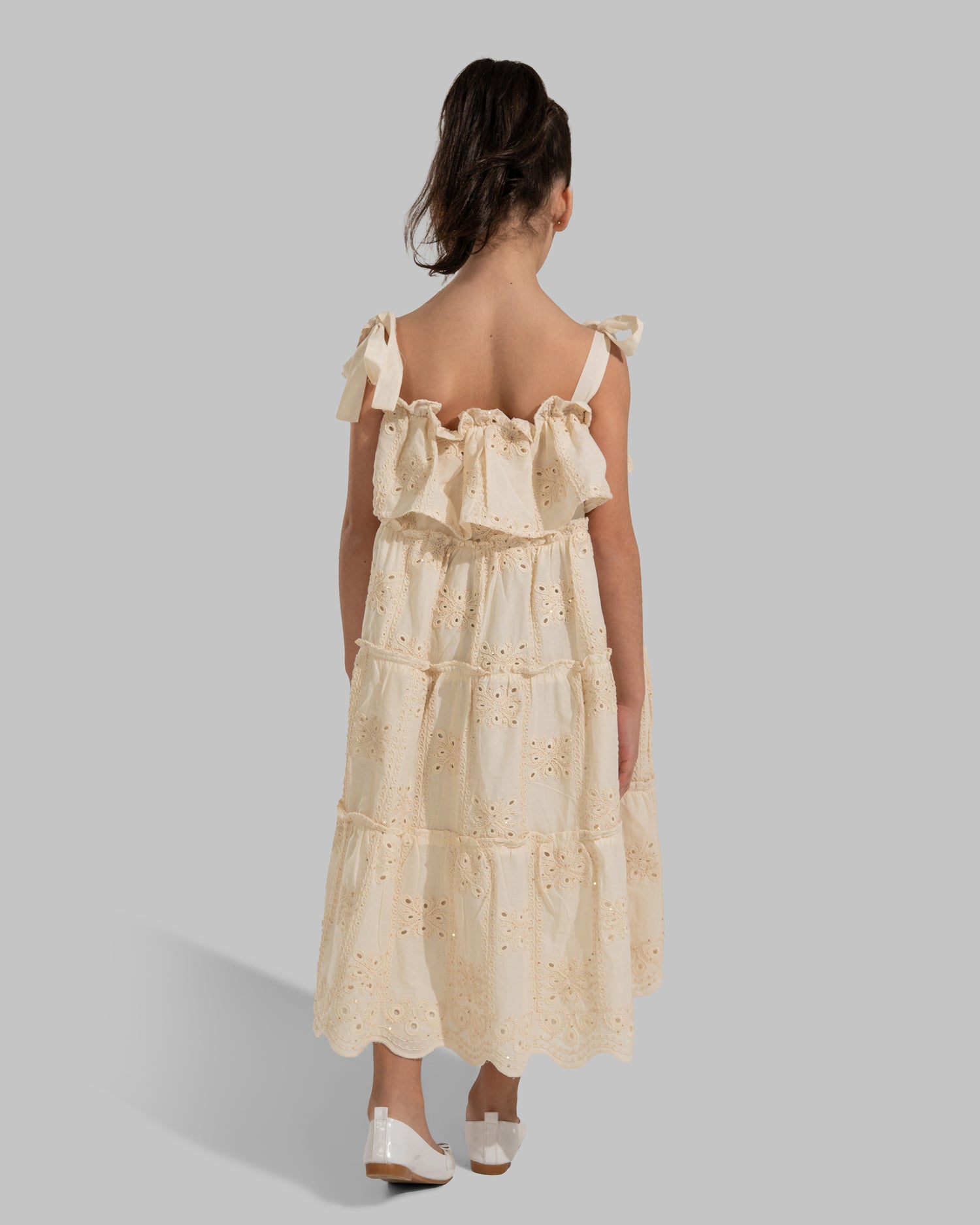 Tiered dress with perforated embroidery, ruffle trim, and tie-up shoulder straps.