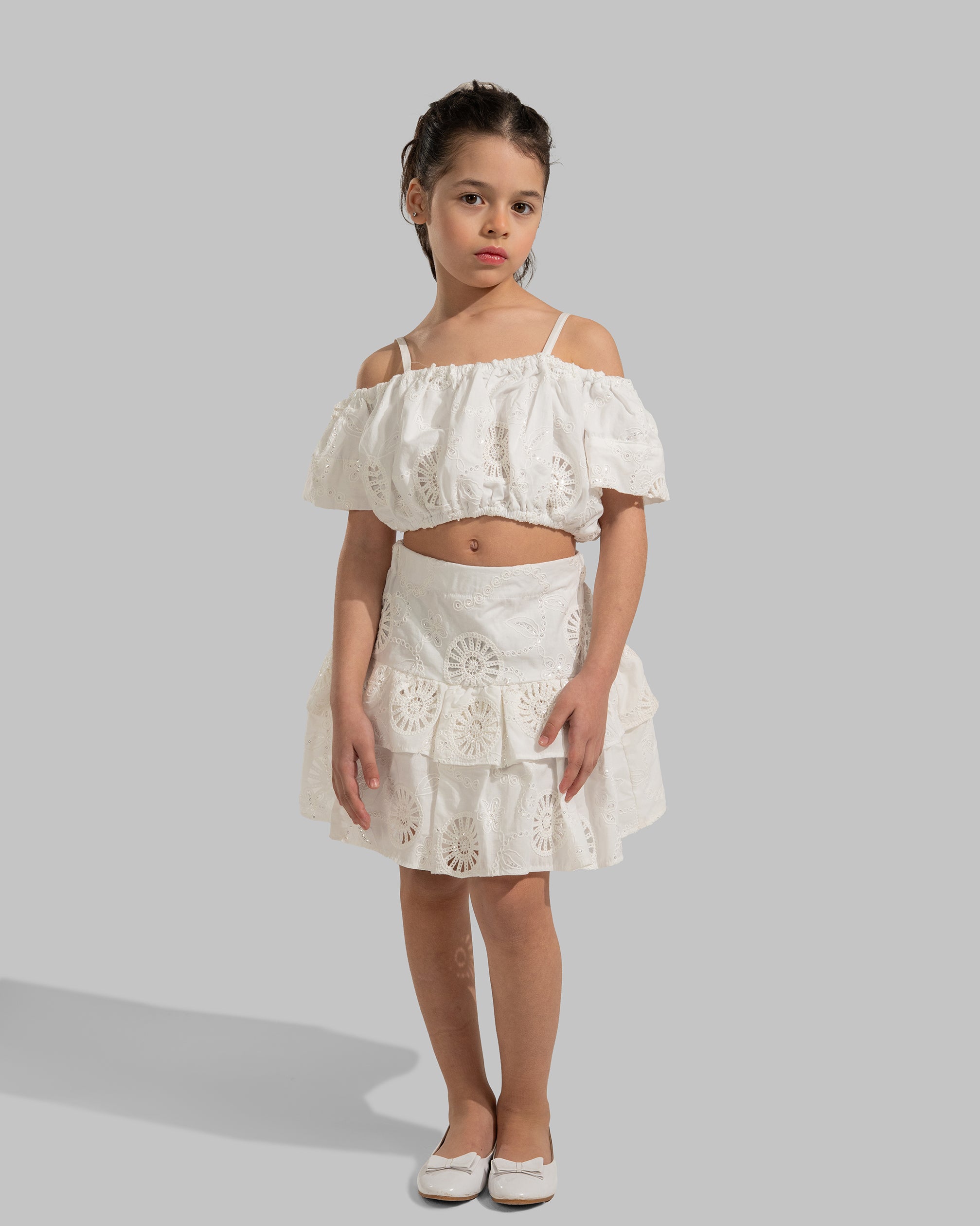 Off-the-shoulder white eyelet crop top with thin straps.