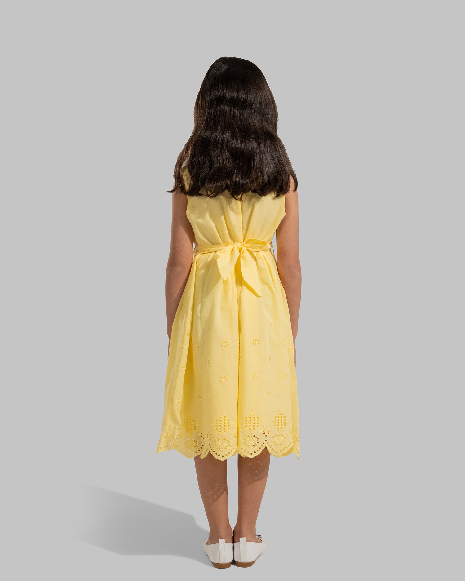 sleeveless pink cotton eyelet dress featuring a floral appliqué on the chest and a matching waist belt.