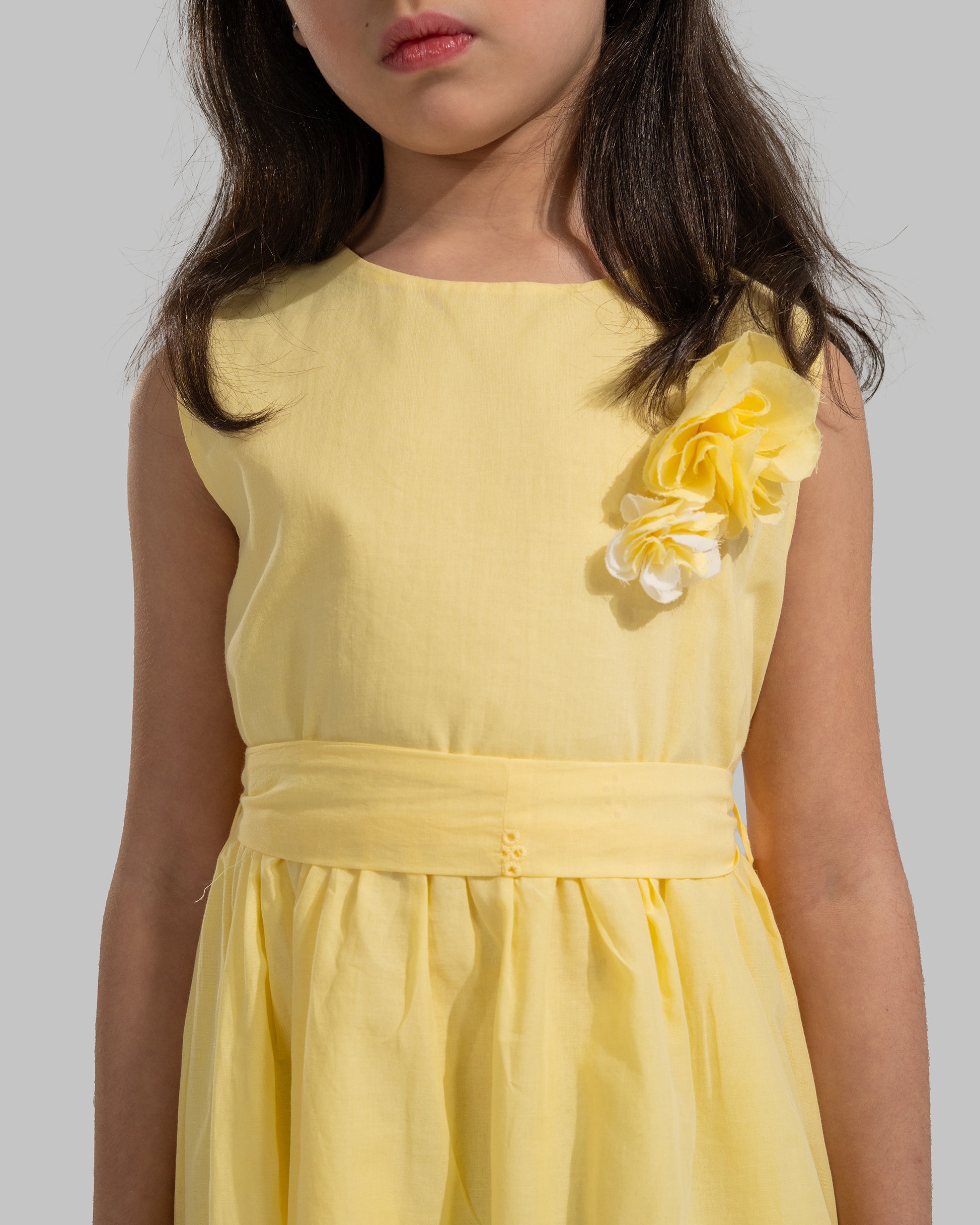 sleeveless pink cotton eyelet dress featuring a floral appliqué on the chest and a matching waist belt.